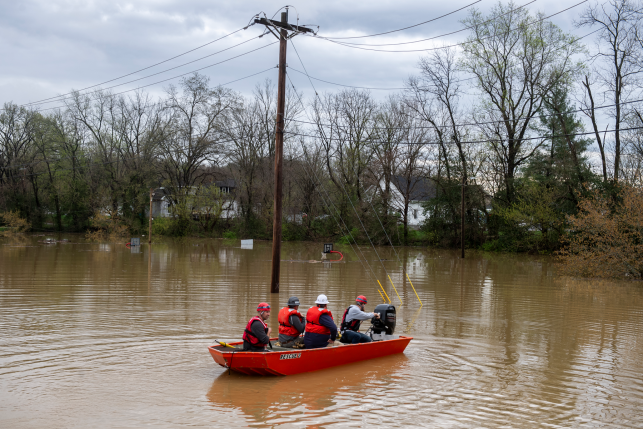 Group of search and rescue workers in a boat surrounded by flood waters in a rural area