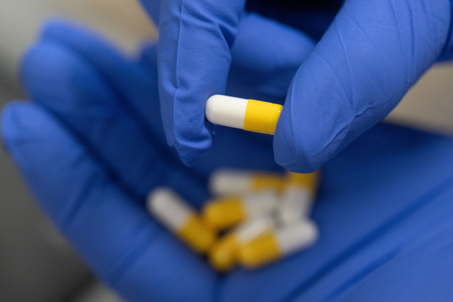 Pills in blue-gloved hands