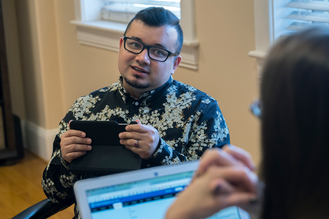 Man on phone talks to woman on laptop