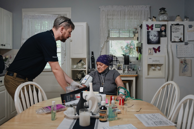 Paramedic helps patient at dining room table