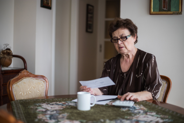 Senior woman sitting at table calculating bills