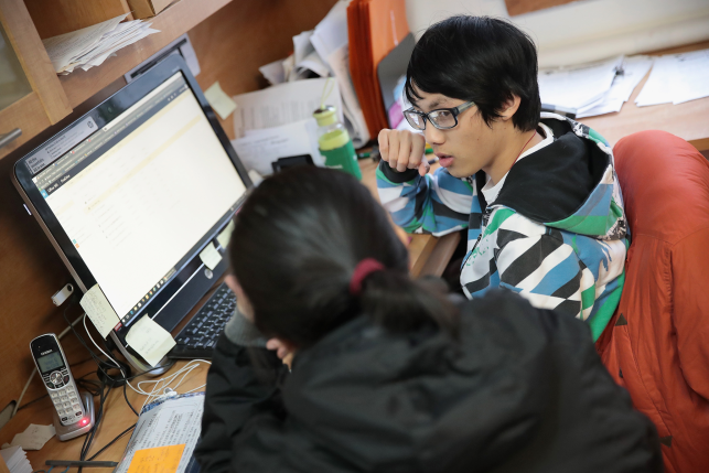 Photo, man and woman talk in front of computer screen