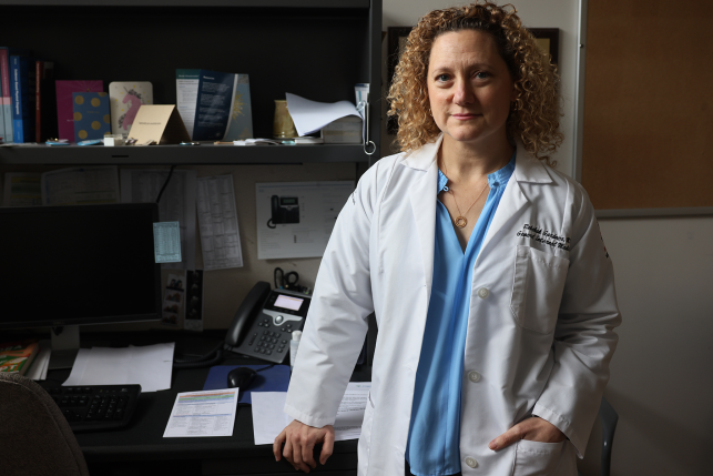 Doctor in white coat stands in front of desk