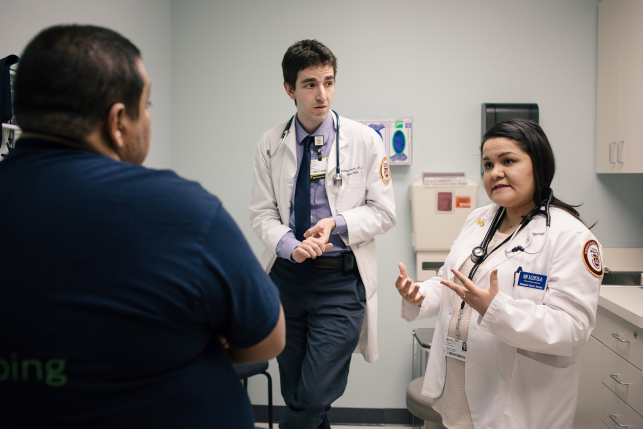 Two doctors talk to patient in clinic