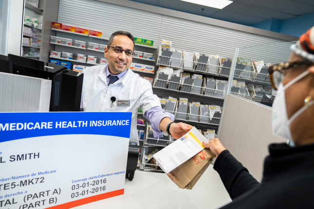 Photo, pharmacist hands bag to patient