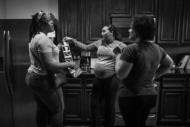 Three women in kitchen looking at sonogram