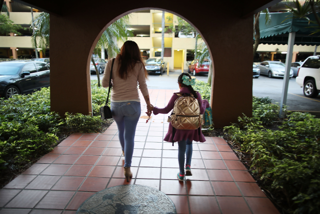 Image, mom and daughter walk hand in hand thru archway