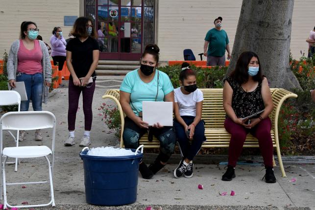 Masked people sitting on a bench after getting flu shots at a walk-up health clinic