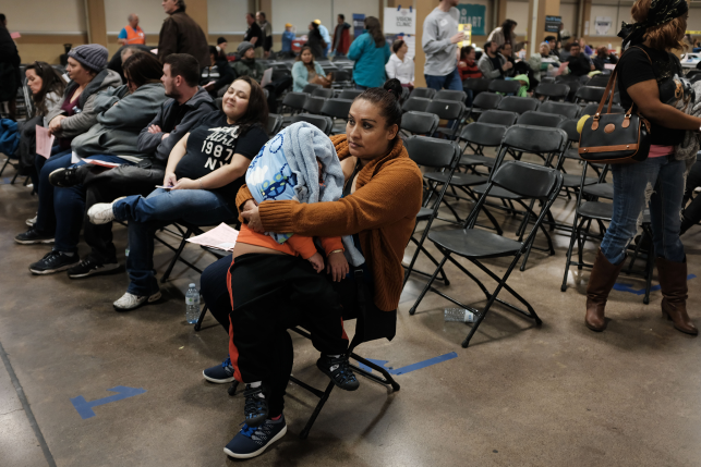 Mom and child sit in waiting room with tons of chairs of health clinic