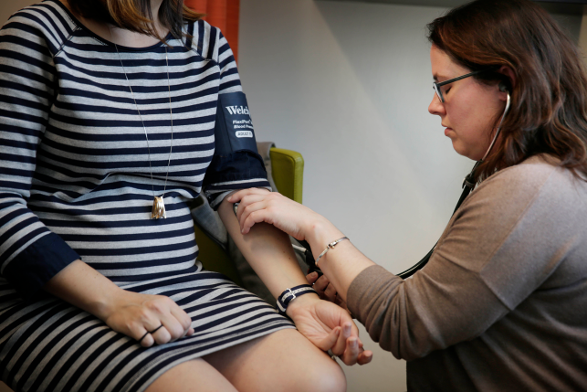 doctor checks female pregnant patients bloodpressure with cuff