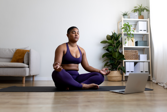 Woman does yoga in front of a laptop