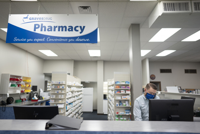 pharmacist with mask stands behind counter