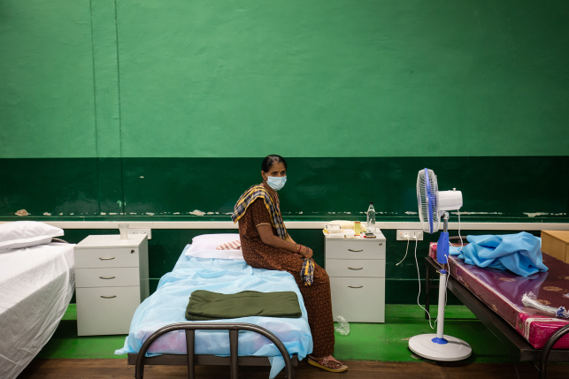 Indian patient sits on hospital bed with mask in Indian hospital room