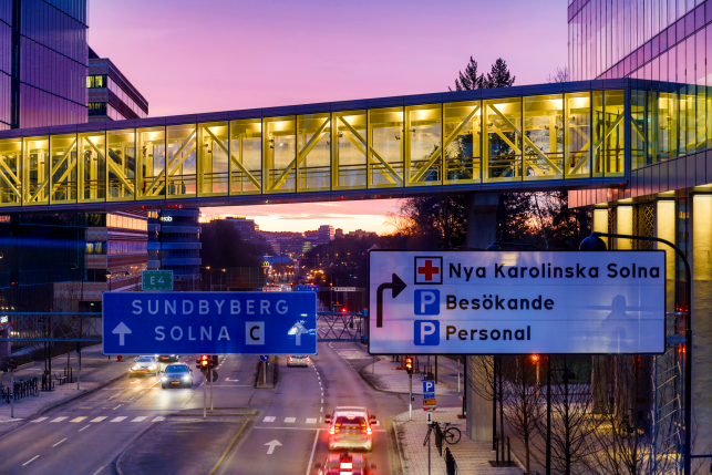 Footbridge suspended over traffic intersection with signs to hospital in Sweden