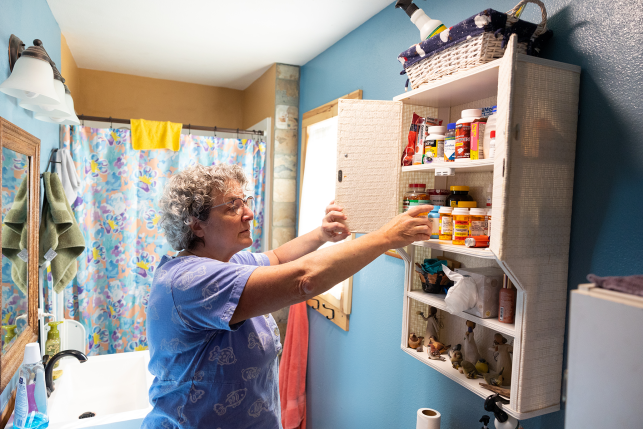 Photo, woman reaching into medicine cabinet