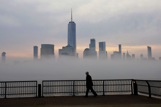 Solitary man in mask looking at NYC skyline in fog