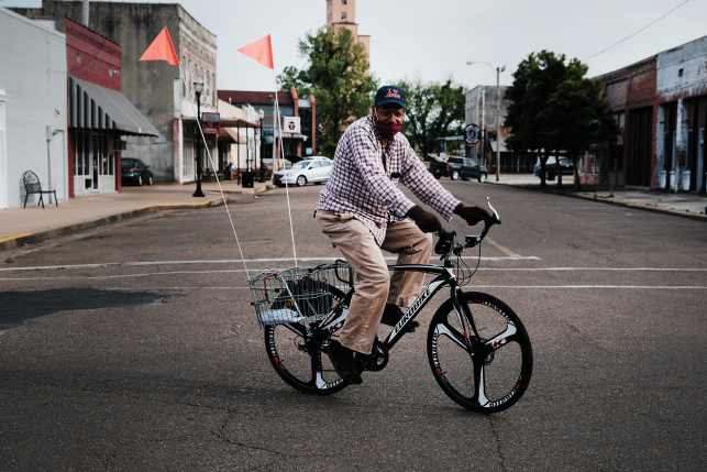 Man in mask rides in neighborhood on bike