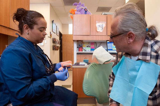 Dental hygienist shows teeth to dental patient in clinic