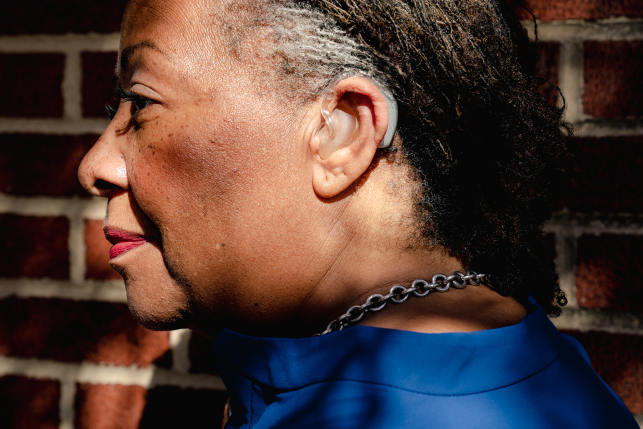 Profile of woman's face with hearing aid over and behind her ear