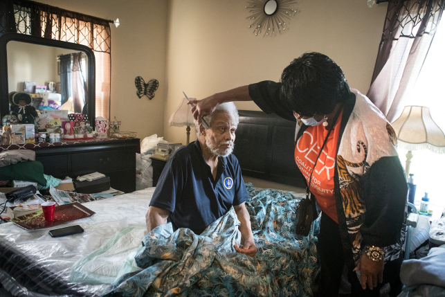 Photo, woman brushing mans hair while he sits up in bed