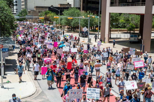 Protestors hold signs and walk down street with pro-choice messages