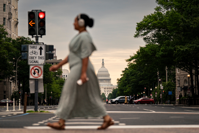 Pedestrian with headphones crosseds pedestrian in front of Capitol building