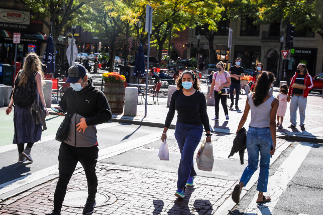 people in masks walk in town square