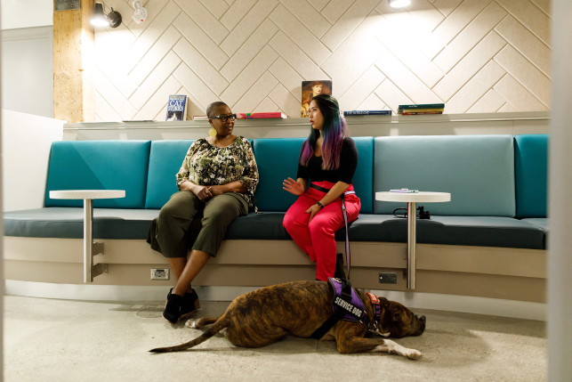 Two women sit on bench with puppy on floor