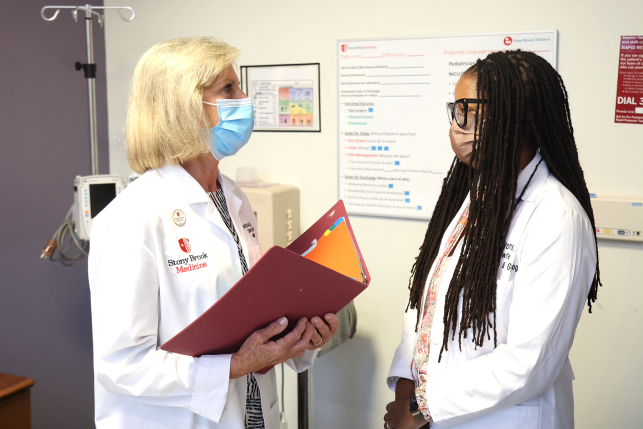 Photo, two midwives in masks talk to each other