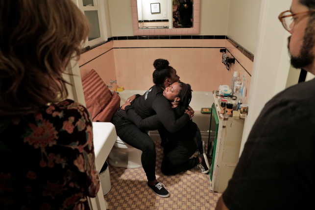 Doulas demonstrating how a birthing person can be supported while in hte bathroom