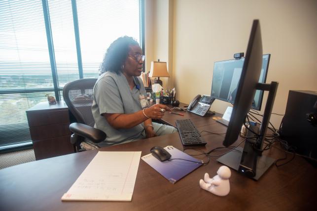 Nurse sits talking at computer meeting virtually with patient