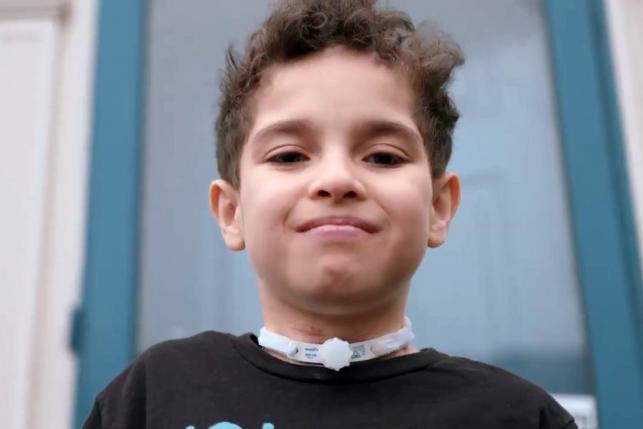 Ten-year-old Isaac smiling in front of his house