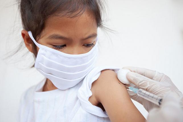 masked girl gets immunization