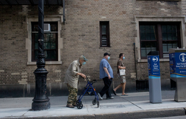Elderly man in mask walks down city sidewalk