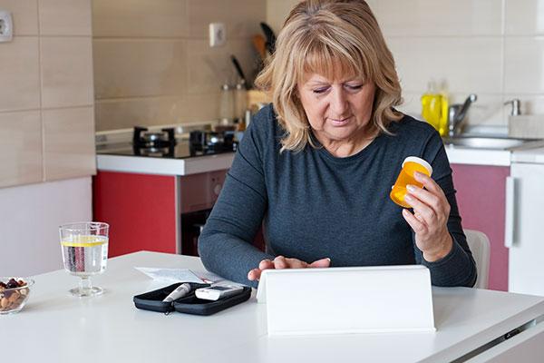 woman doing telehealth while checking blood sugar at home