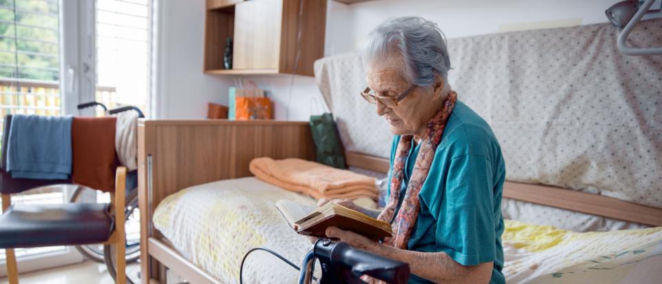 Medicare senior who is seriously ill reading on bed