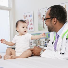 Baby on doctors table reaches for doctor