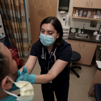 Photo, Doctor examines patients throat with her gloved hands.