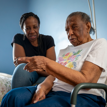 Woman smiles at her mother in a wheelchair