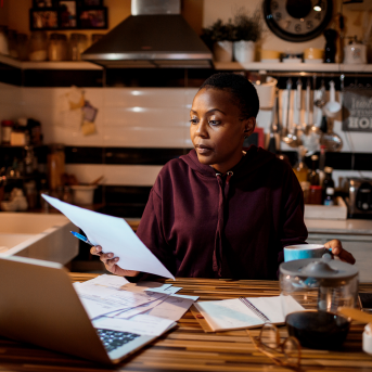 woman looks at paperwork in kitchen