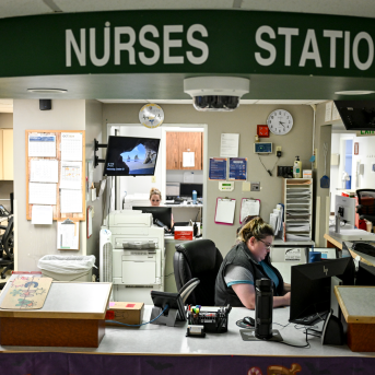 Nurses working at computers in a cluttered hospital nurses station 