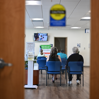 backs of people seen through waiting room door