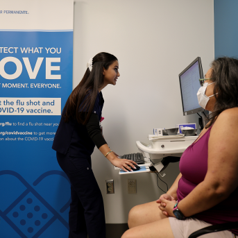 Woman prepares to get covid vaccine, while talking to nurse on computer.