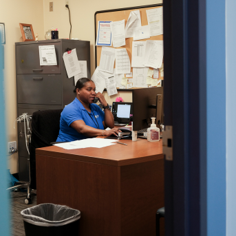 photo, woman sits behind desk on phone