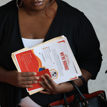 Woman holds up paperwork and folder in front of her chest.