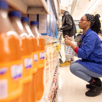 Grocery store employee looks at products in aisle