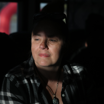Middle-aged woman looks on pensively shrouded in shadows