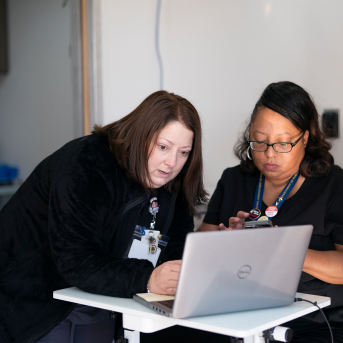 two clinic workers look at laptop