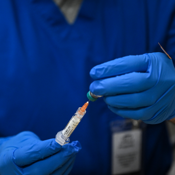 Gloved hands hold syringe