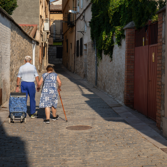 Elderly copy walks arm in arm through Spanish street